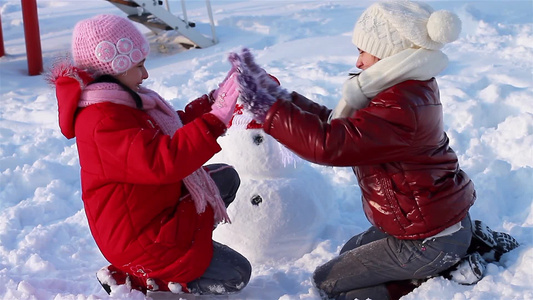 女孩们在雪地里游戏堆雪人视频