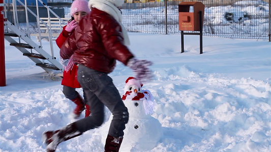 快乐的女孩围着圣诞雪人跑视频