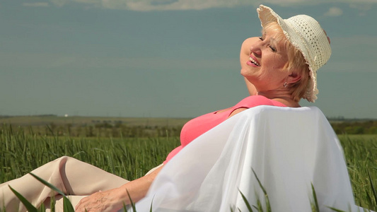女人坐在田野上沐浴阳光视频