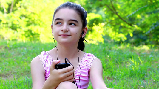 女孩在公园里用智能手机听音乐视频