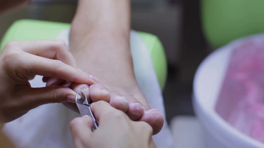 美容院足疗师在给做足疗的女孩修剪脚指甲视频