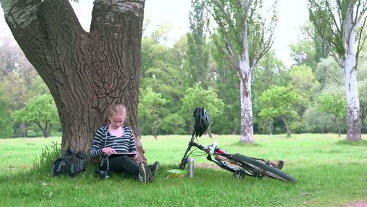 坐在树下玩平板听歌的女孩视频