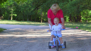祖母带孩子在公园里学习骑自行车9秒视频