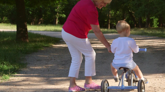 祖母协助孙子在公园骑自行车视频