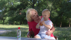 在公园里奶奶抱着喝果汁的孩子12秒视频