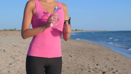 在海边健身休息时喝水的女孩[男孩儿]视频