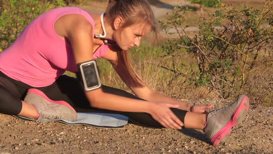 健身的年轻女人在户外运动前伸展腿视频