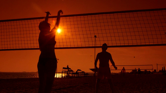 假期夕阳下一对对年轻人在海边打沙滩排球视频