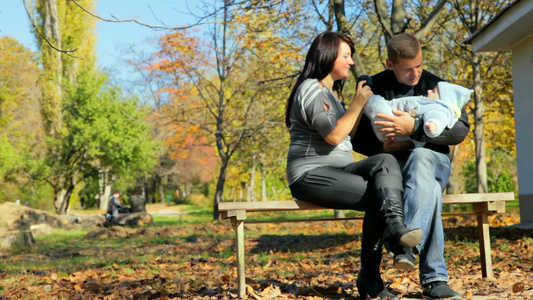 父亲抱着婴儿和妻子一起坐在公园的长凳上视频