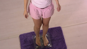 中年妇女站在体重秤上看到体重数据达到减肥目标时脸上露出高兴的笑容14秒视频
