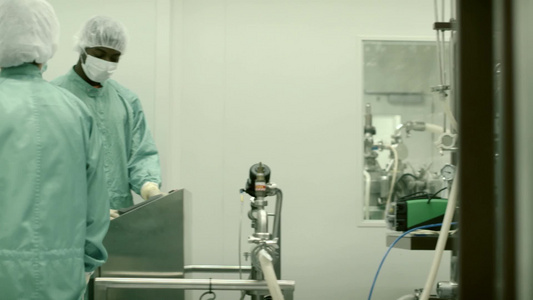 在医疗工厂工作的实验室技术人员使用机械和计算机视频
