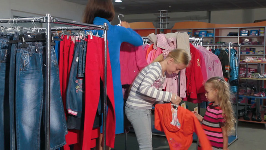 中年妇女带着孩子在一家服装店里买衣服视频