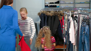 母亲带着两个女儿在一家服装店里为孩子们挑选搭配的裙子和毛衣29秒视频