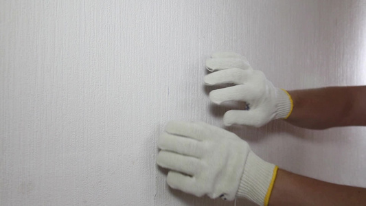 戴手套的人展示了如何移除旧壁纸视频