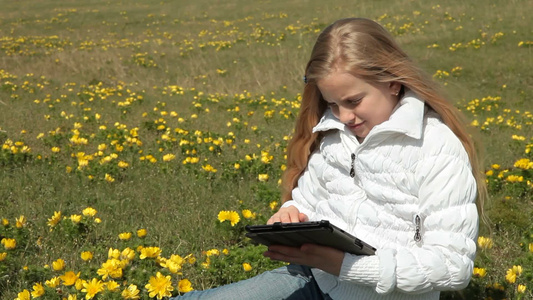 坐在草地上玩平板电脑的女孩[绿茵茵]视频