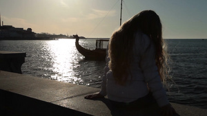 日落海边堤坝上女孩吹风休息9秒视频