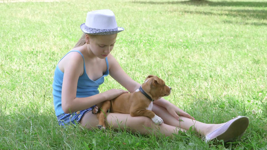 小女孩带着小狗坐在绿色的草坪上视频