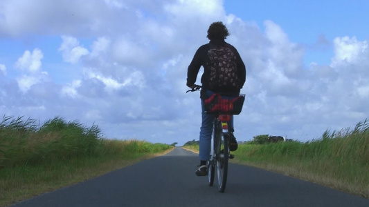 晴朗的天气年轻人骑着自行车在郊外乡村的路上视频