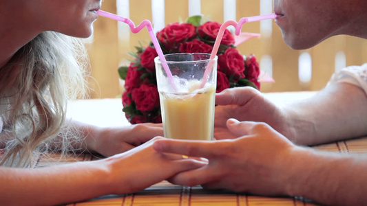 情侣在咖啡馆用一杯橙汁喝视频