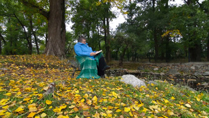老年妇女在秋季公园读书10秒视频