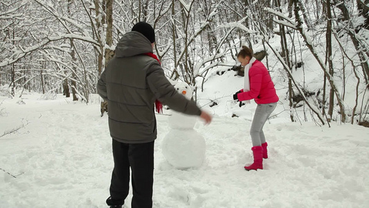夫妇在冬天的雪林里堆雪人视频
