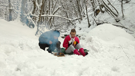 一对夫妇在雪林里生火视频