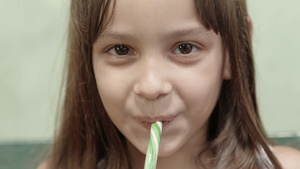 可爱的小女孩吃着糖果棒微笑着看着相机14秒视频
