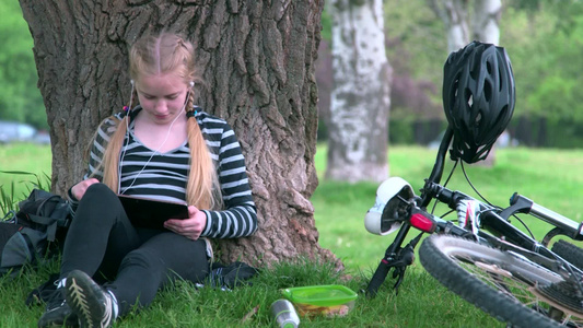 女孩在公园草地上看平板电脑视频
