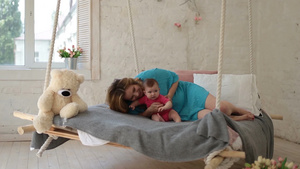 美丽的年轻母亲躺在床上和她可爱的宝贝女儿玩耍10秒视频