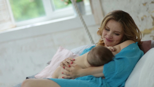 美丽的年轻母亲的抱着看着她的婴儿在喂乳[迷人]视频
