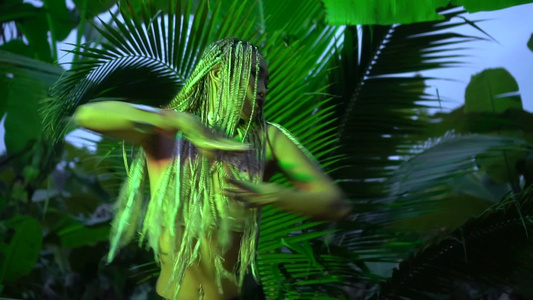美丽的扎着绿色辫子的女人在丛林中的棕榈树附近跳舞低角度视频视频