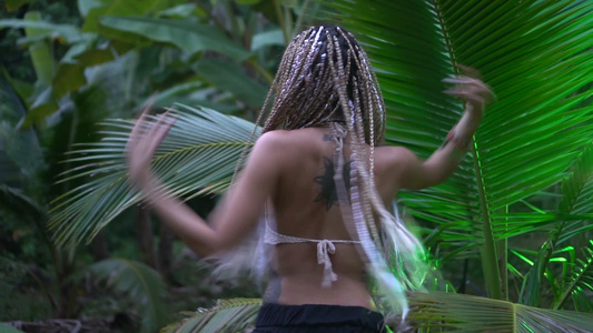 美丽的女人在丛林中的棕榈树附近跳舞视频