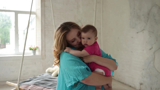 美丽的年轻母亲和亲吻婴儿在客厅里享受幸福时光视频