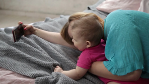 母亲和她的孩子躺在床上玩手机15秒视频