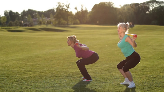 侧视图迷人的成年金发女性在公园草坪上锻炼视频
