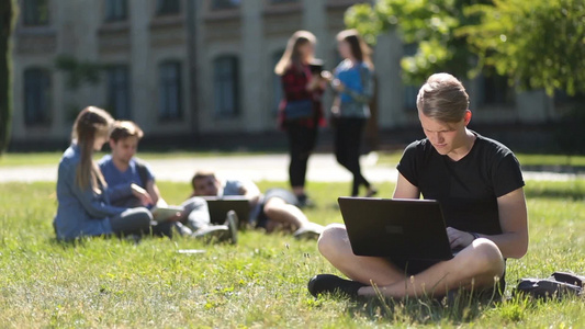 大学生在校园草坪上做学习视频