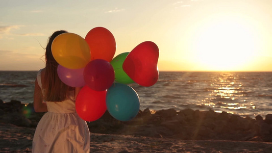 拿着气球的金发女人站在海边视频