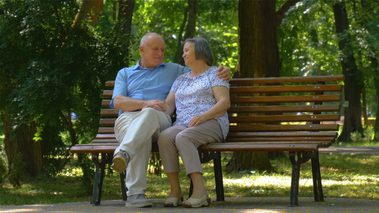 老年夫妇在夏天公园坐在长凳上聊天[条凳]视频