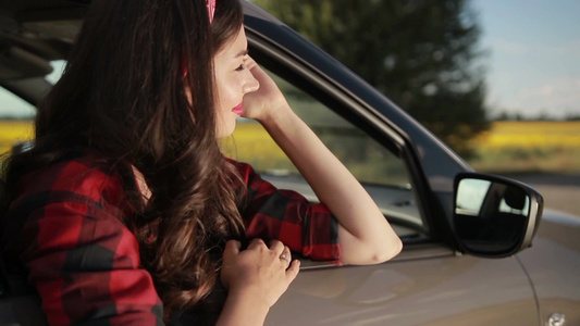 美丽的年轻女孩涂着红色口红坐在车里天真和灿烂的微笑着看着窗外的风景视频