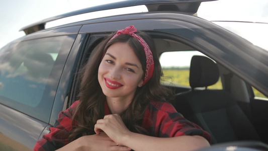  迷人的年轻女人从车窗外斜倚着车窗微笑着对着镜头视频