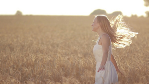快乐的金发女人穿着白色的连衣裙在金色的麦田里自由自在地旋转11秒视频