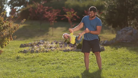 草坪上父亲和蹒跚学步的孩子玩耍[踉踉跄跄]视频