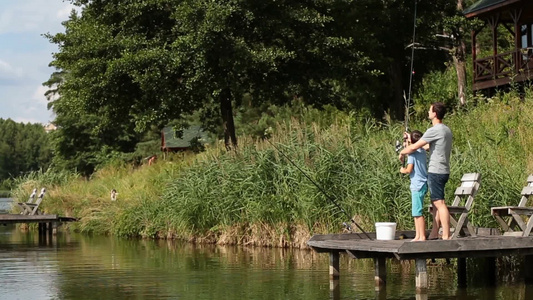 慈爱的父亲教他的十几岁的男孩如何在湖面上钓鱼视频