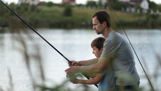 年轻的男子和小男孩在湖边钓鱼视频