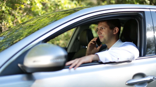 年轻商务男人坐在汽车上用手机与商业伙伴沟通视频