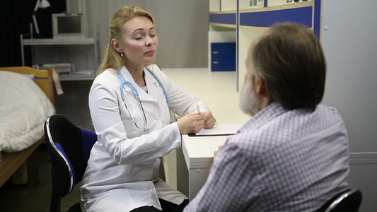 漂亮的年轻女医生在诊所细心的接受老年男性患者咨询视频