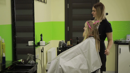 开朗的女理发师在美容院剪女孩的金发视频