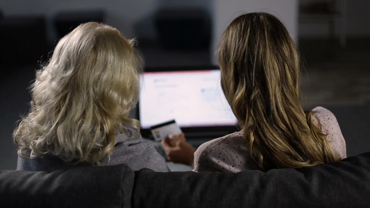 两名女士用电脑和信用卡在线购买视频
