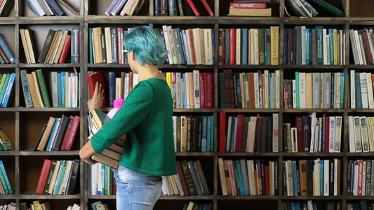 蓝头发的学生在书架前挑选书籍视频