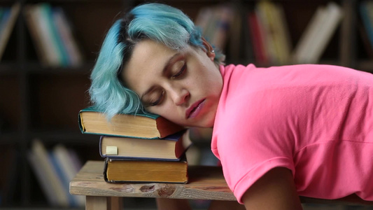 迷人的时髦女孩睡在图书馆的一堆书上视频